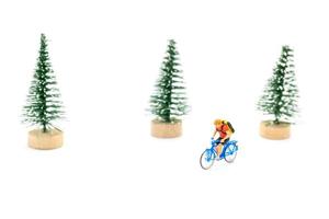 Miniature people with gifts on a bicycle on white background photo