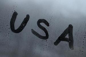 The English abbreviation USA is written with a finger on the surface of the misted glass. United States of America photo