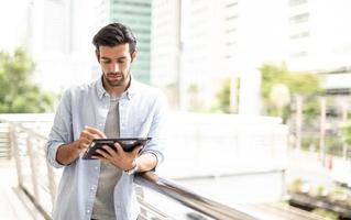 The young man using a tablet to working at out of office. The man wearing casual cloth and feeling thinking and seriously. photo