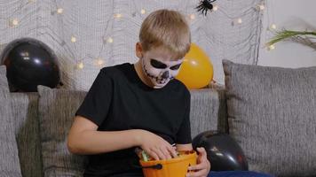 um menino com maquiagem de esqueleto tira doces de uma festa de halloween. época festiva em outubro. video