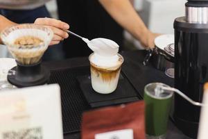 Barista making iced latte coffee with hand topped whipping in cafe. photo