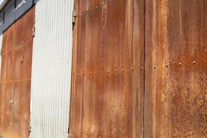 Rusty gates. More of gate to warehouse. Old wall. photo