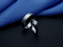 anillo de bodas de oro blanco. anillo de pareja con acabado brillante y apagado con fondo azul y negro foto