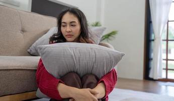 Unhappy asian pretty young woman siting alone on couch with feeling sadness photo