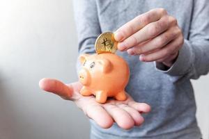 Man hand holding piggy bank with cryptocurrency golden bitcoin coin. Electronic virtual money for web banking and international network payment. Symbol of crypto virtual currency, Mining concept photo
