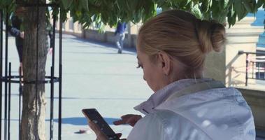 Ein Mädchen an einem sonnigen Herbsttag am Ufer des Schwarzen Meeres sieht sich Informationen auf ihrem Telefon an video