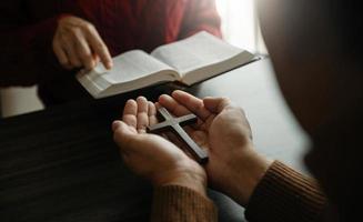 Two people reading and study bible in home and pray together.Studying the Word Of God With Friends. photo