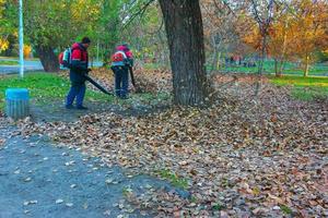 dnipro, ucrania - 10.30.2021 trabajadores en la calle en otoño recogen hojas con un soplador foto