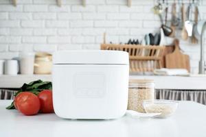 Electric rice cooker on wooden counter-top in the kitchen photo