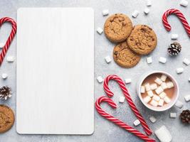 The chocolate chip cookie, Christmas cane caramel Cup cocoa and marshmallow cones Decorations on a gray background. Copy space Frame. photo