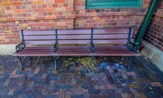 Three Seat Wooden Bench Outside Brick Building photo