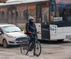 Dnepropetrovsk, Ukraine - 02.10.2022 A delivery service courier with a thermal bag on a bicycle rides around the city. Home food delivery. photo