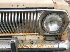 An old retro vintage hipster rusty oxidized chrome-plated metallic silver radiator grille and a round glass retro spotlight of an antiquan white white American car from the 60s, 70s, 80s, 90s, 2000s photo