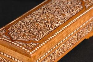 The artistic wood carving on the casket on the black background. Central Asia, Uzbekistan, close-up photo