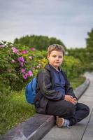 retrato de un niño, un chico en contra el antecedentes de plantas en un aire libre parque. niños, viajar. estilo de vida en el ciudad. centro, calles foto