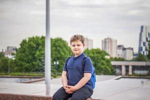 Portrait of a child, a boy against the backdrop of urban landscapes of skyscrapers and high-rise buildings in the open air. Children, Travel. Lifestyle in the city. Center, streets. photo