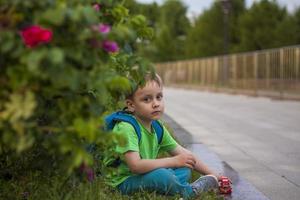 retrato de un niño, un chico en contra el antecedentes de plantas en un aire libre parque. niños, viajar. estilo de vida en el ciudad. centro, calles foto