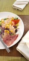 delicious breakfast, ham and fresh summer salad on white plate, on wooden table, view from above photo