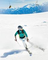 Gudauri, Georgia, 2022 - male skier close up go downhill carving fast motion with mountains background photo