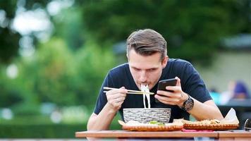 jong Mens aan het eten nemen weg noedels Aan de straat video