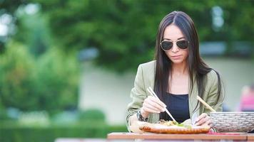 Young woman eating take away noodles on the street video