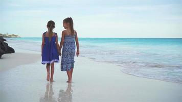 weinig meisjes wandelen door de zee Aan de wit strand. kinderen Aan strand vakantie in de avond video