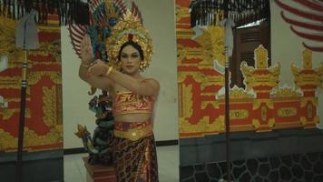 Eine schöne balinesische Frau, die vor einem verzierten Tor mit einer goldenen Krone auf dem Kopf tanzt