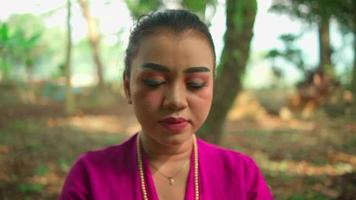 une Javanais femme avec une rose robe souriant avec bonheur tandis que portant or bijoux sur sa cou à l'intérieur le village video
