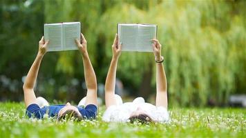 Relaxed young couple reading books while lying on grass video