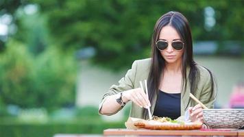 jeune femme mangeant des nouilles à emporter dans la rue video