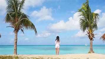 Young beautiful woman on tropical seashore. Happy girl relaxing at white sand tropical beach video