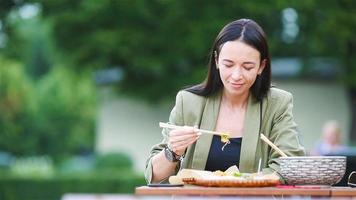 mujer joven comiendo fideos para llevar en la calle video