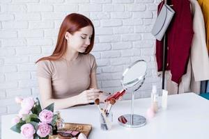 mujer joven maquillando en casa, usando sombras de ojos foto