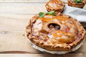 pastel de carne casero con vegetación sobre fondo de madera foto