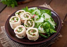 Steamed chicken rolls with greens and fresh vegetable salad on a brown plate photo