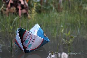 Gorontalo-Indonesia, November 2022 - Paper boat on water on green grass background photo