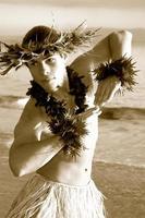 sepia Clásico Mira de un masculino hula danza ejecutando en el arena siguiente a el océano. foto