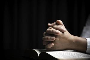 Faith with holy bible concept. Hands of a female prayer worship God with holy bible on black background in church. Christian woman who believe in Jesus read and study the grace of the holy scriptures. photo