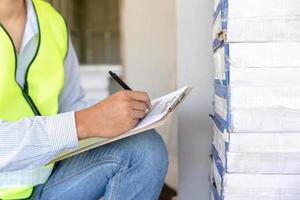 inspector or engineer is inspecting construction house using a checklist. Engineers and architects or contactor count materials for construction. Building, check, insurance house, quality, foreman. photo