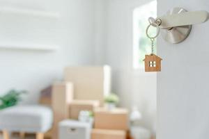 Moving house, relocation. The key was inserted into the door of the new house, inside the room was a cardboard box containing personal belongings and furniture. move in the apartment or condominium photo