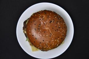 Double hamburger with meat on a white plate. Hamburger on a black background. photo