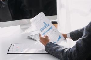 Asian Business woman using calculator and laptop for doing math finance on an office desk, tax, report, accounting, statistics, and analytical research concept photo