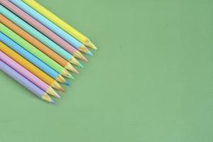Pastel colored pencils, top view on green background, illustration concept, education and back to school photo