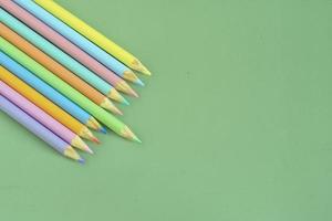 Pastel colored pencils, top view on green background, illustration concept, education and back to school photo