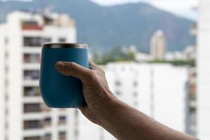 hand holding a mug of water with a view on the city background photo