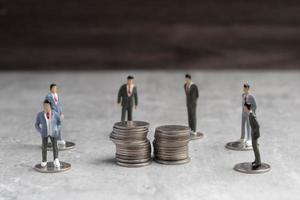 Miniature people standing around coins, business man shaking hands during a meeting, success, dealing, greeting and partner concept. photo