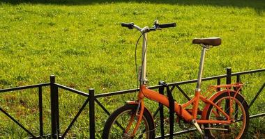 Walking compact city bike on green grass background with copy space. City tourism and bike rental service photo