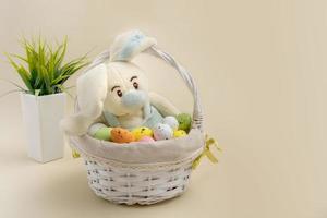 funny bunny in an easter basket among eggs on a beige background, easter content photo