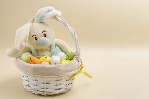 funny bunny in an easter basket among eggs on a beige background, easter content. photo