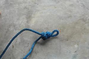 Blue knotted rope isolated with whitish gray wall photo